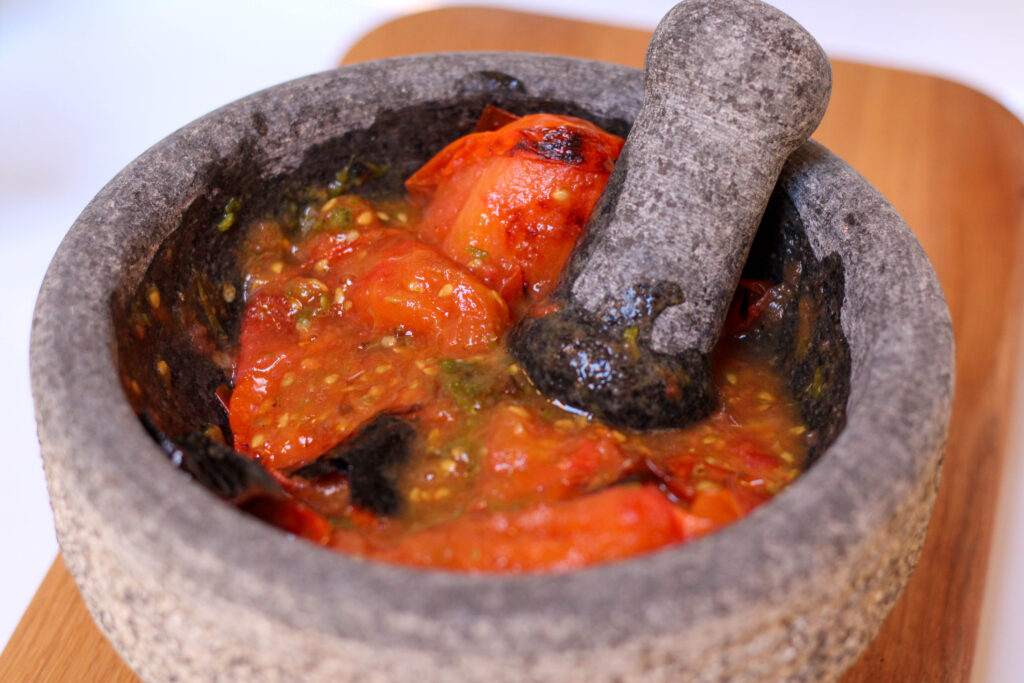 Roasted tomatoes, serrano chiles and garlic mashed in a molcajete or mortar and pestle. Authentic Mexican Salsa de Molcajete Recipe