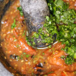 Authentic Mexican Salsa de Molcajete. Roasted tomato salsa in a mortar and pestle with cilantro