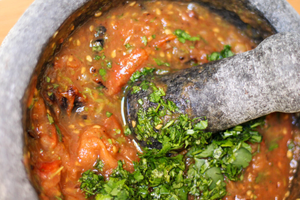 Red Mexican salsa in a molcajete with cilantro on top. Authentic Mexican Salsa de Molcajete Recipe