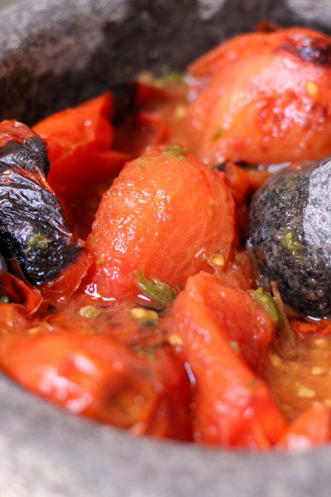 Roasted tomatoes, serrano chiles and garlic mashed in a molcajete or mortar and pestle. Authentic Mexican Salsa de Molcajete Recipe