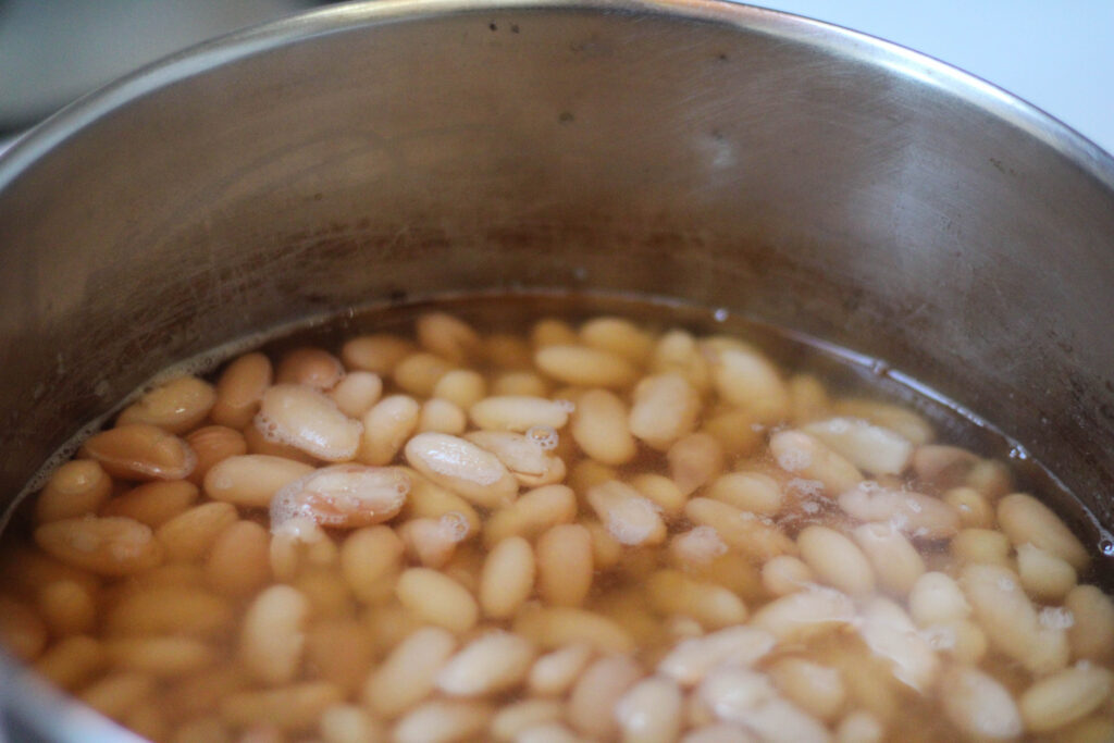 Peruvian Beans in a pot with water on stove. Cooking Peruano beans in water. Boiling Mayocoba beans in water on stovetop. 