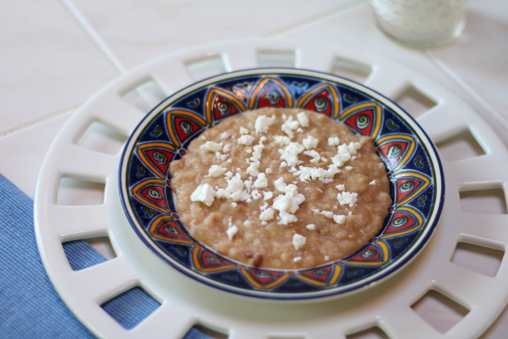 Frijoles refritos served on a plate, topped with cheese with a white background. Mexican refried beans on a plate.