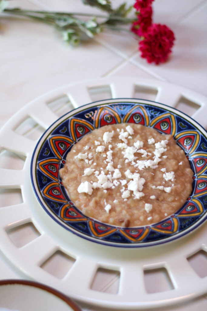 Frijoles refritos served on a plate, topped with cheese with a white background. Mexican refried beans on a plate.