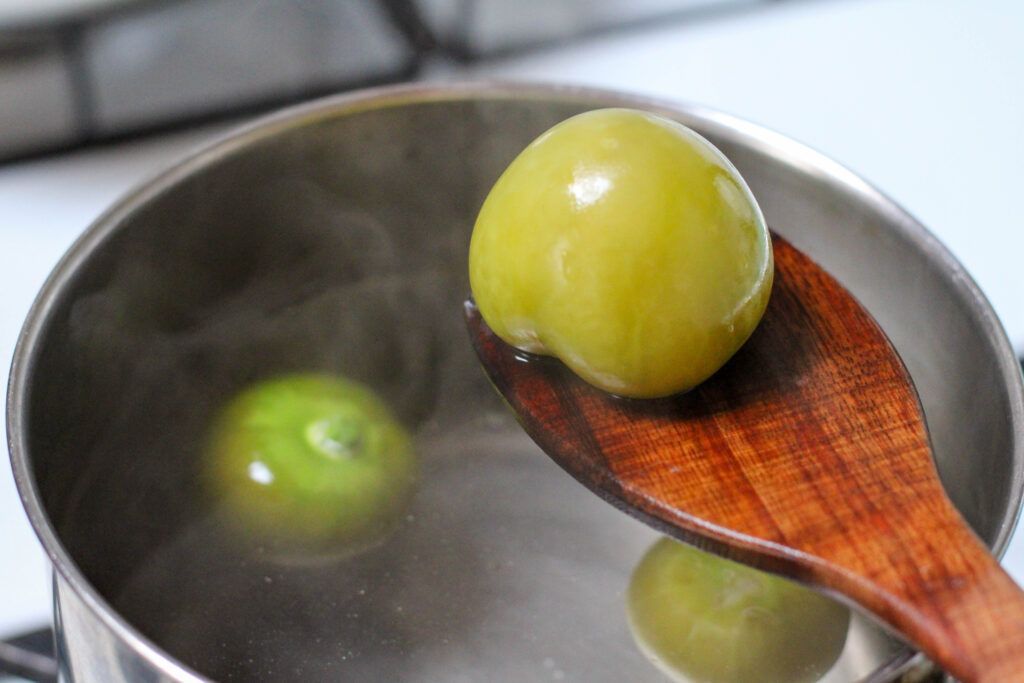 Tomatillos for salsa for tacos boiling in a saucepan on the stove. 