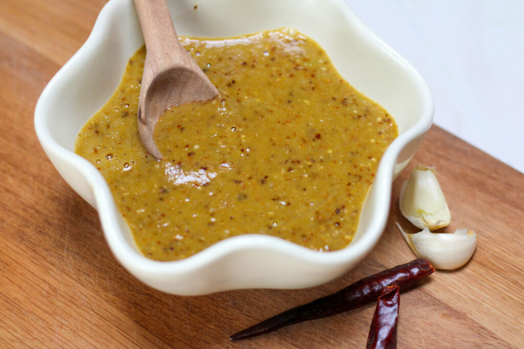 Salsa de chile árbol in a white bowl with wooden spoon. Easy and spicy salsa for tacos in a bowl with chile de árbol. 