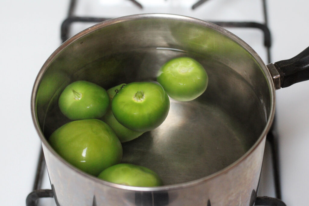 Tomatillos for salsa for tacos boiling in a saucepan on the stove. 