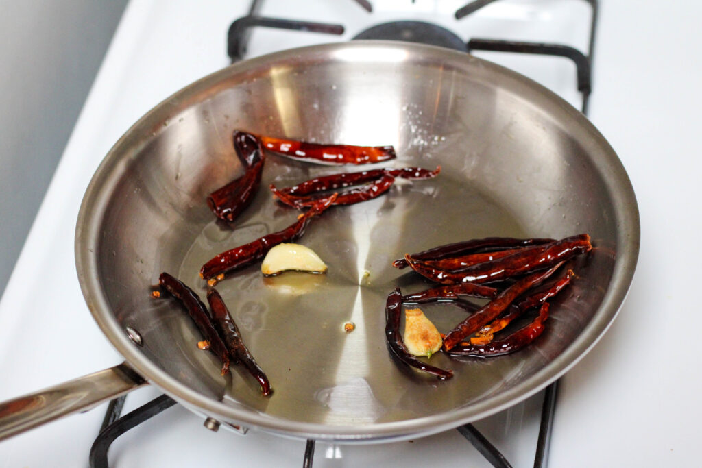 Chile de árbol and garlic fried in oil in a frying pan. 