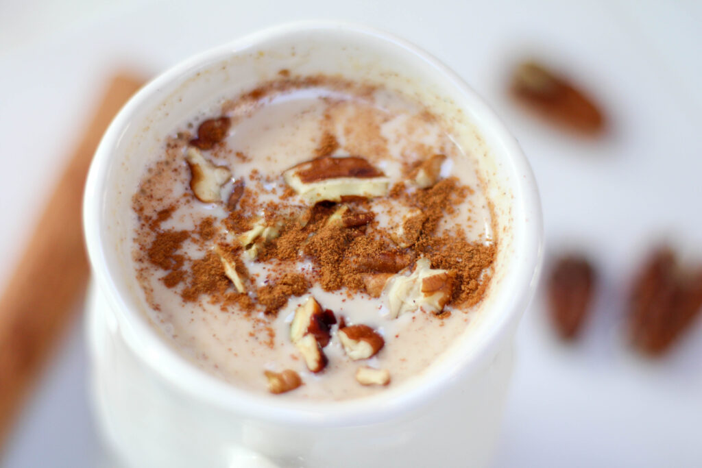 Atole de Nuez served in a white mug topped with cinnamon and chopped pecans.