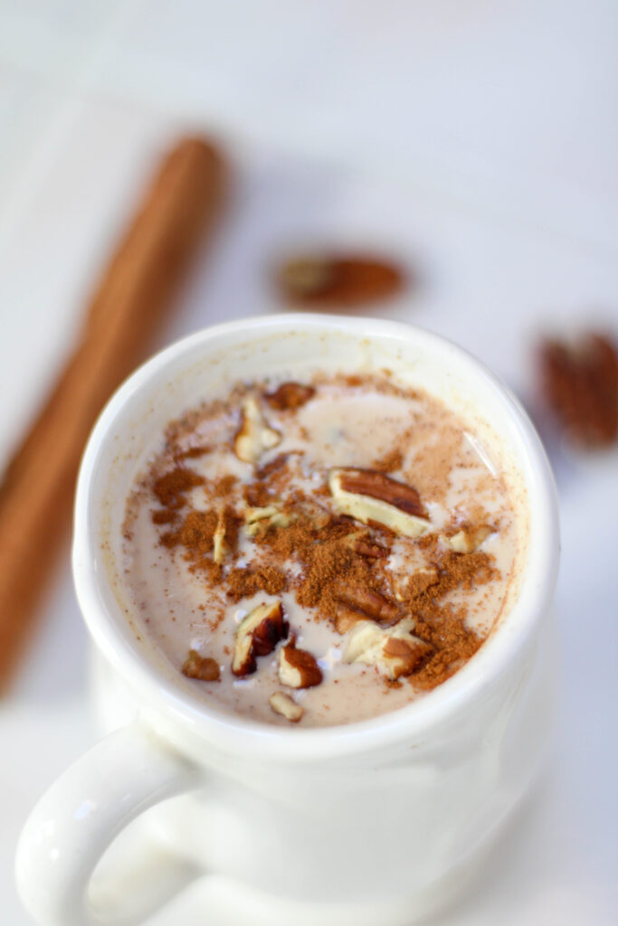Atole de Nuez served in a white mug topped with cinnamon and chopped pecans.