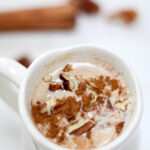Atole de Nuez served in a white mug topped with cinnamon and chopped pecans.