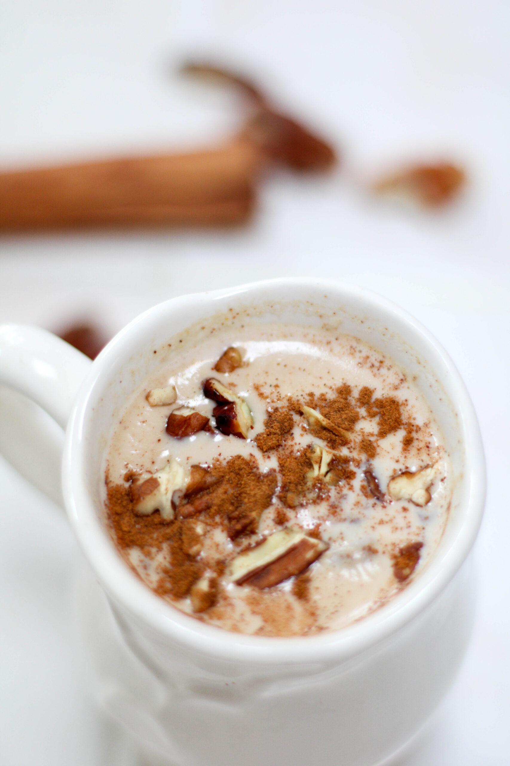 Atole de Nuez served in a white mug topped with cinnamon and chopped pecans.