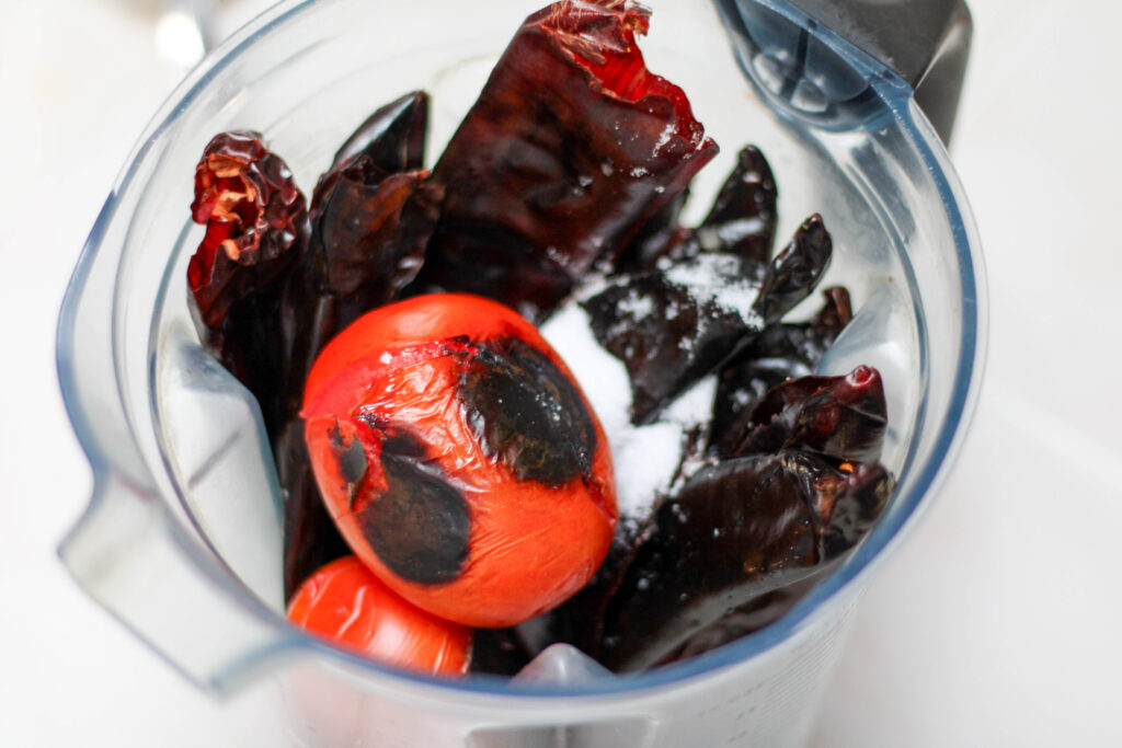 Blender filled with guajillo  chiles, garlic, two tomatoes and salt. 