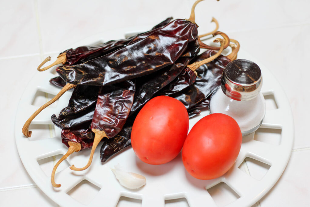 Chiles guajillos, tomatoes and salt on a white place with white background. 