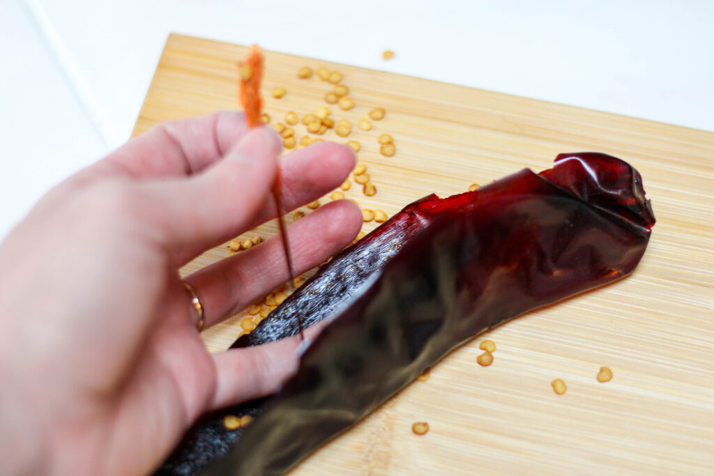 Hand removing the seeds and pith from a guajillo chile. 