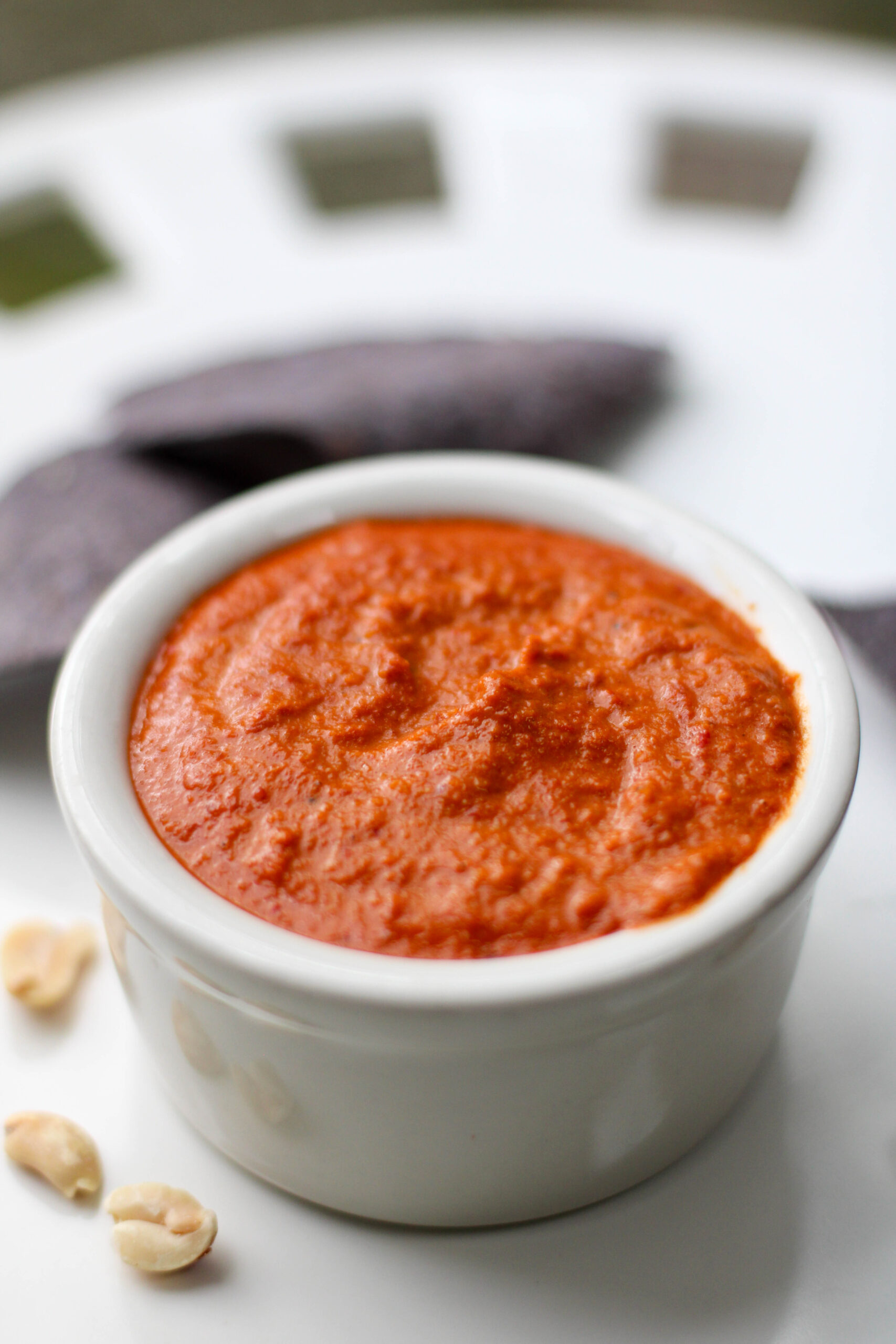 Salsa de cacahuate in a small white serving dish with white background.