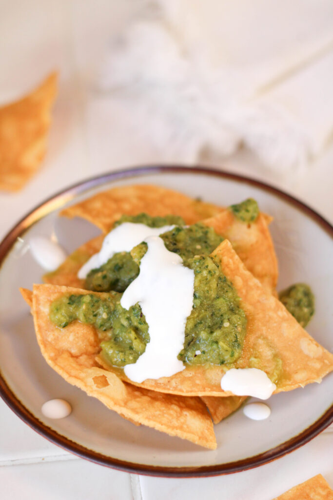 Chips on a plate topped with salsa de calabaza and crema.
