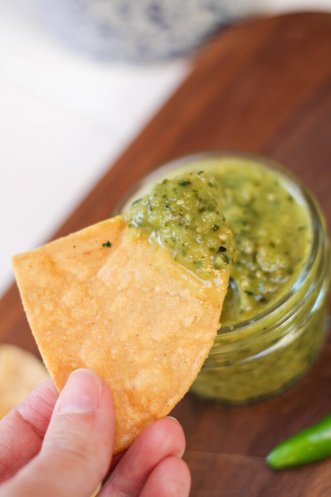 Hand holding chip dipped in Salsa de calabaza. 