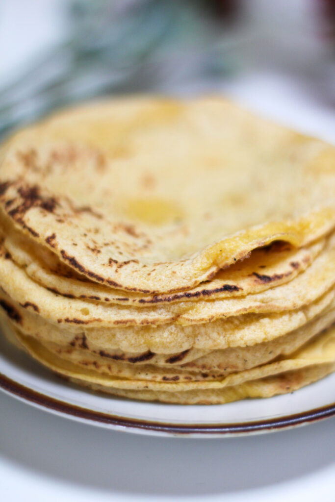 Tortillas a mano stacked on a plate on a white table. 