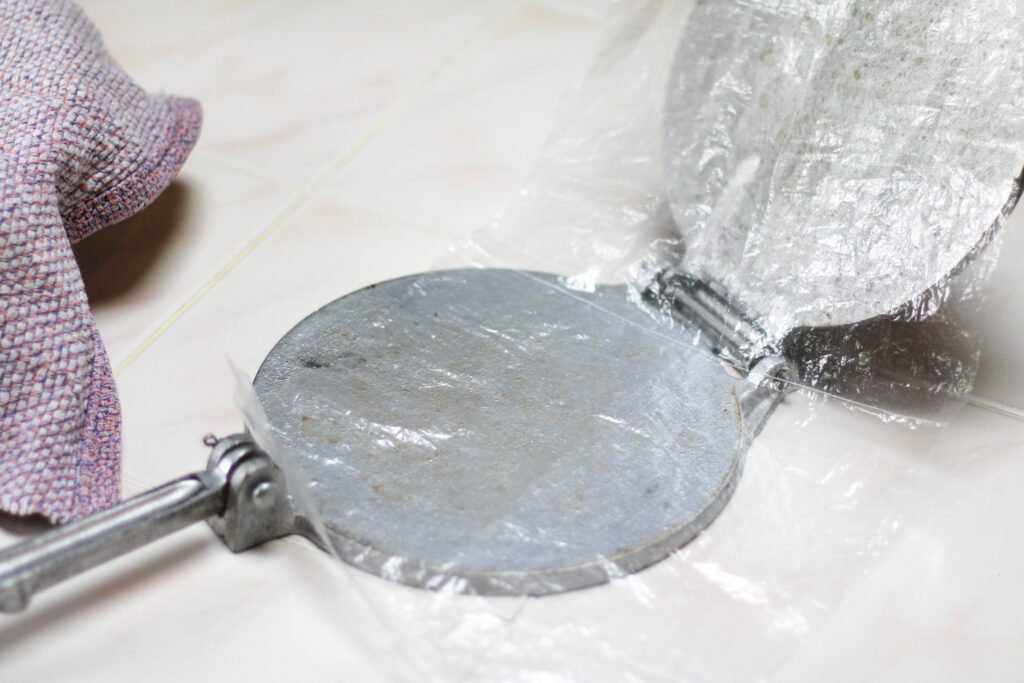 Tortilla press with plastic sheet on top for making corn tortillas. 