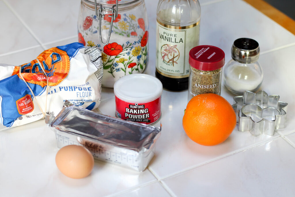 Ingredients for bizcochito cookies including flour, sugar, vegetable shortening, orange, baking powder, etc.