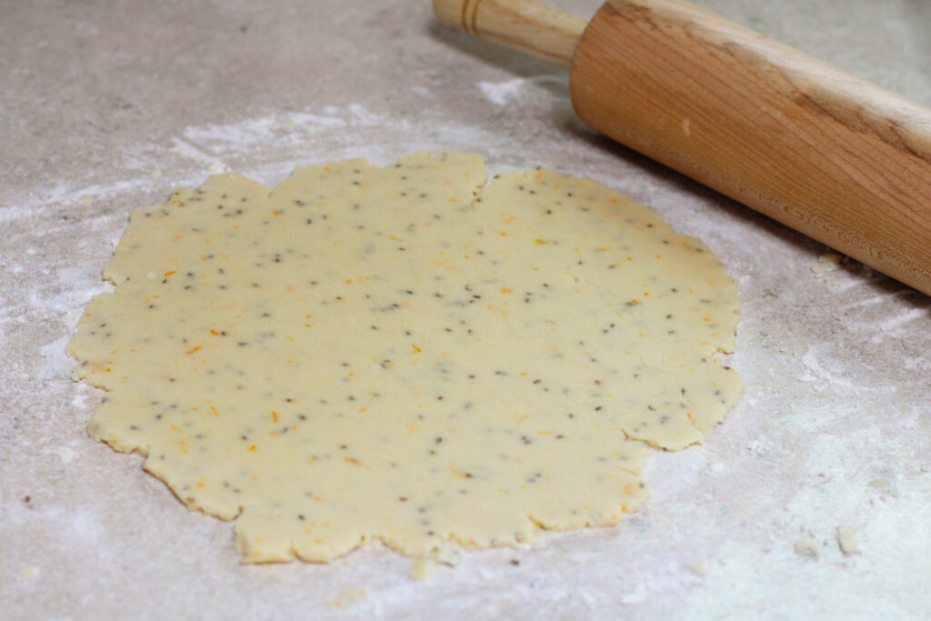 Cookie dough rolled out on a floured surface with rolling pin.