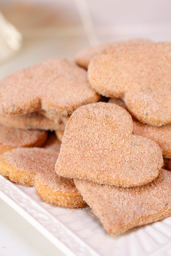 Heart shaped bizcochitos cookies on a white plate.