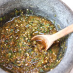 Roasted serrano salsa in a molcajete with wooden spoon.
