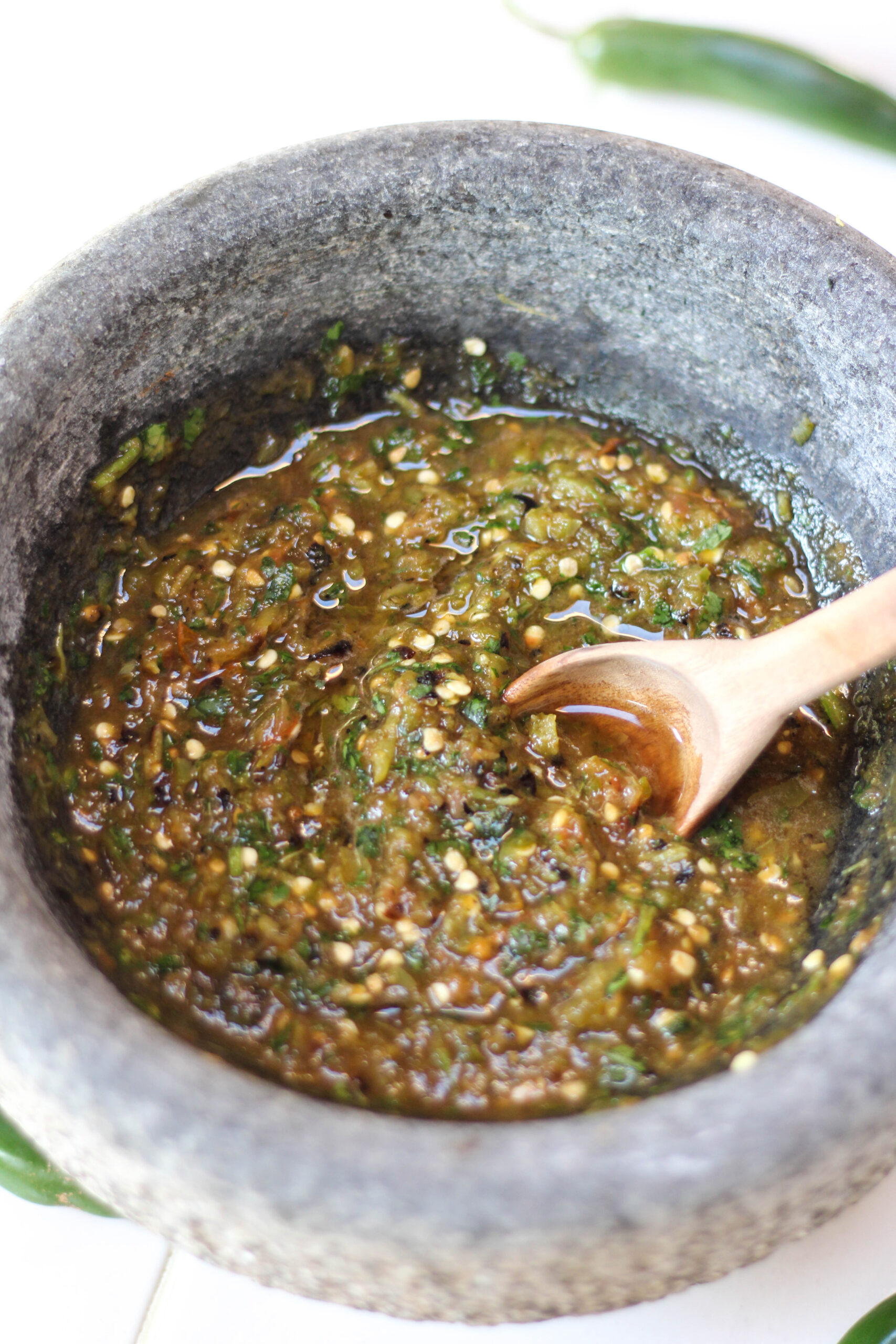 Roasted serrano salsa in a mortar and pestel or molcajete with wooden spoon.