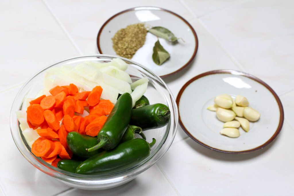 ingredients for jalepenos en escabeche including chopped carrots, sliced onion, jalepenos, garlic and spices