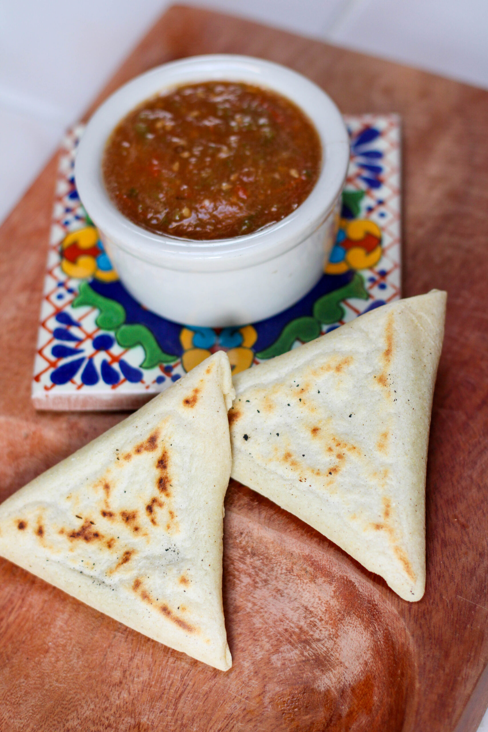 two tetelas on a wood serving dish with red salsa
