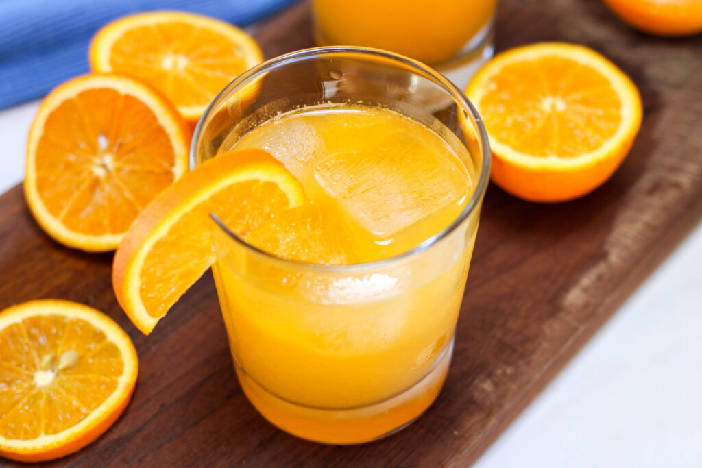 Glass of naranjada con soda with orange slices in the background