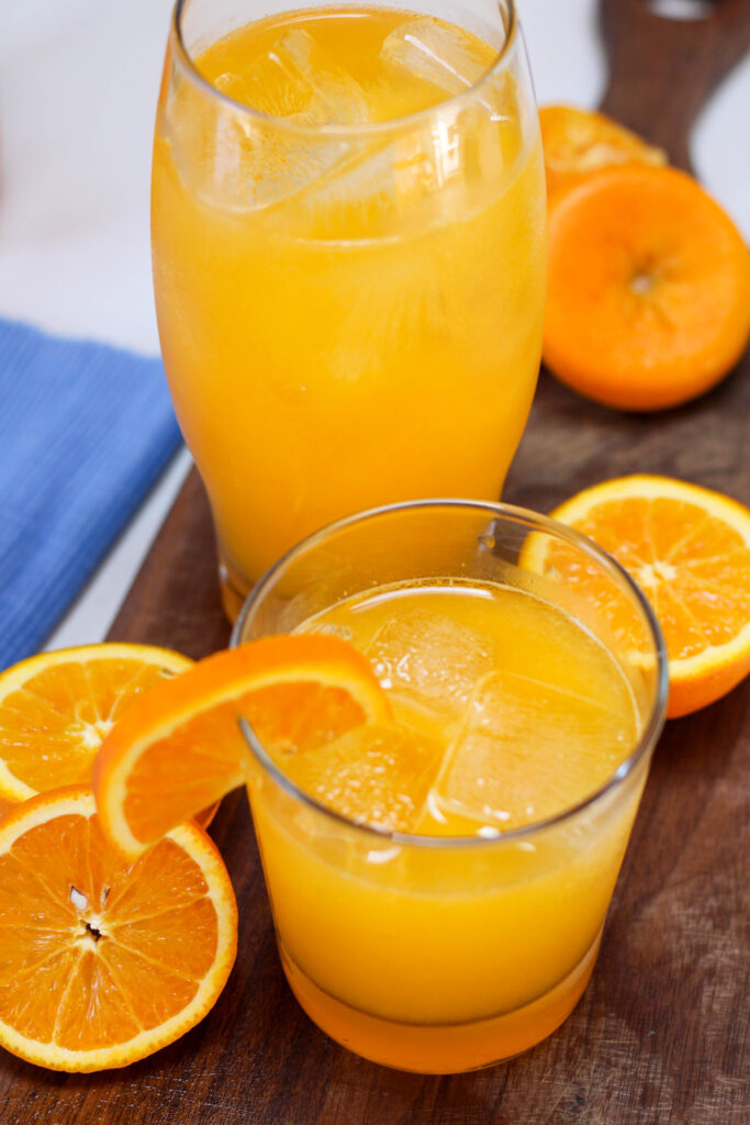 Glasses of naranjada mineral with orange slices in the background