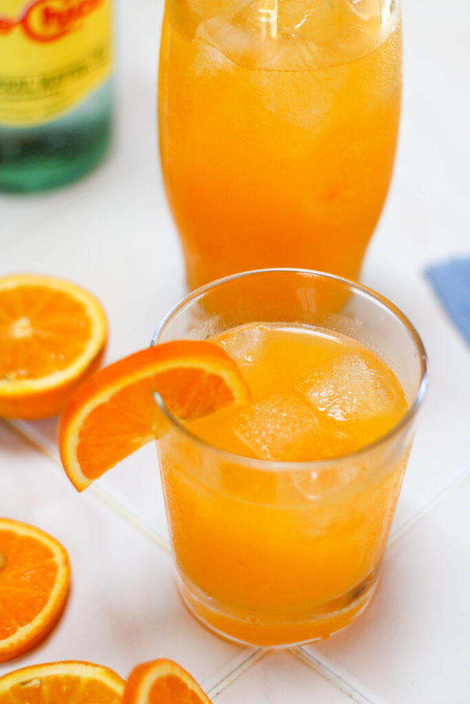 Two glasses of naranjada mineral garnished with orange slices.