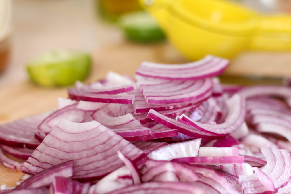 sliced red onion with limes in the background