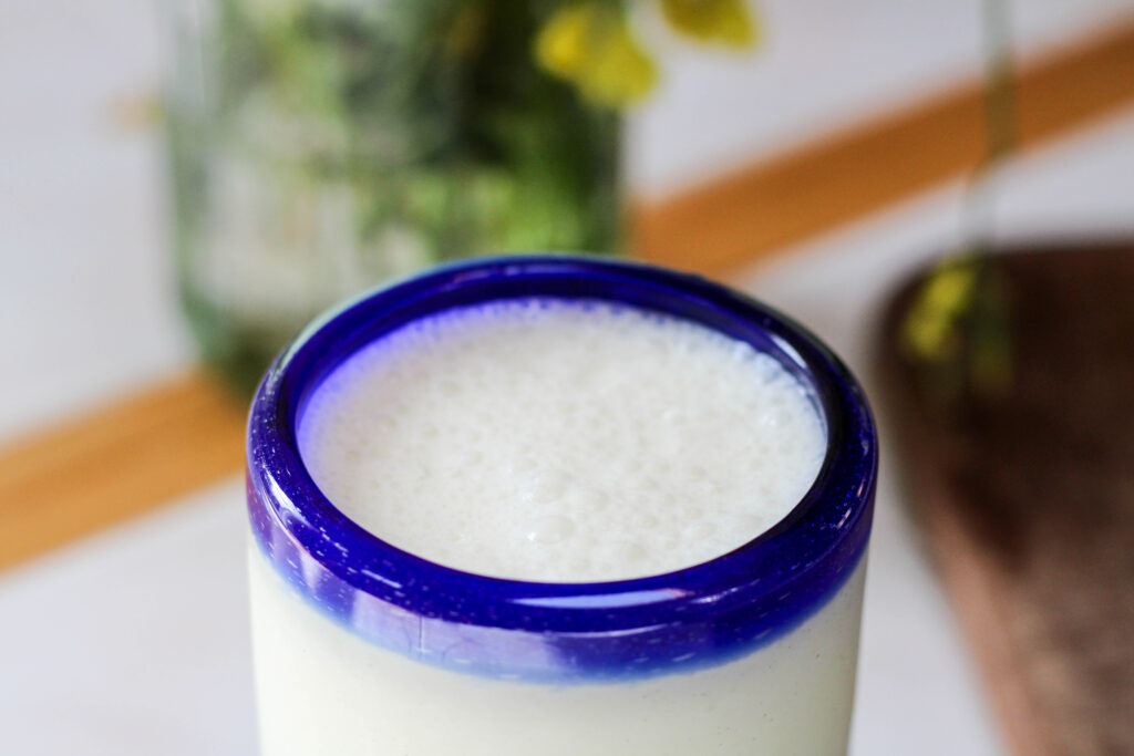 Virgin piña colada in a blue rimmed glass with white background