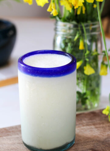 Glass of non alcoholic pina colada with yellow flowers in the background