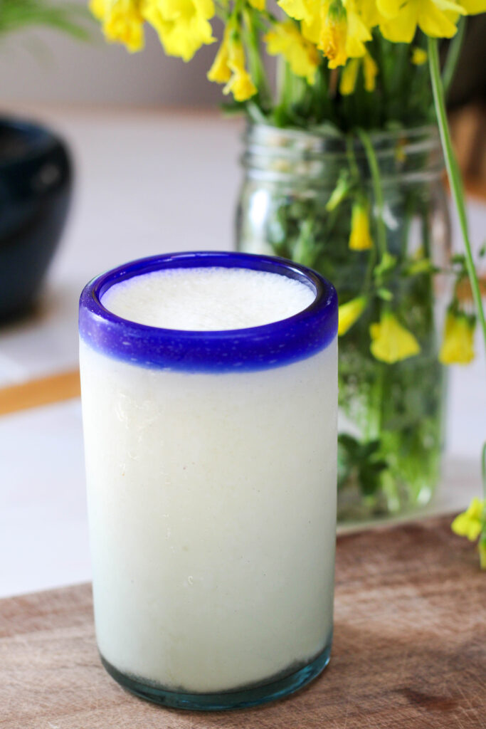 Glass of non alcoholic pina colada with yellow flowers in the background