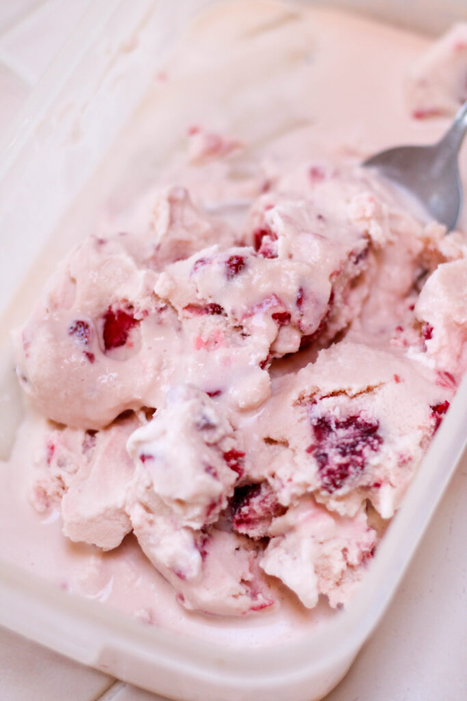 Large container of helado de fresa with a white background
