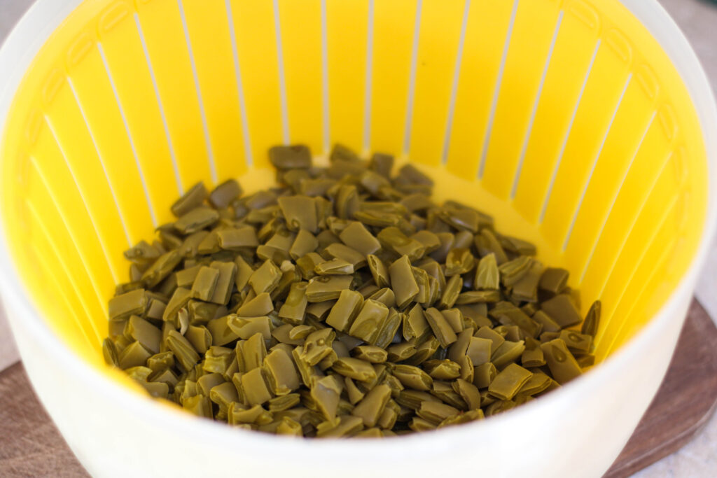 Nopales draining in a yellow strainer