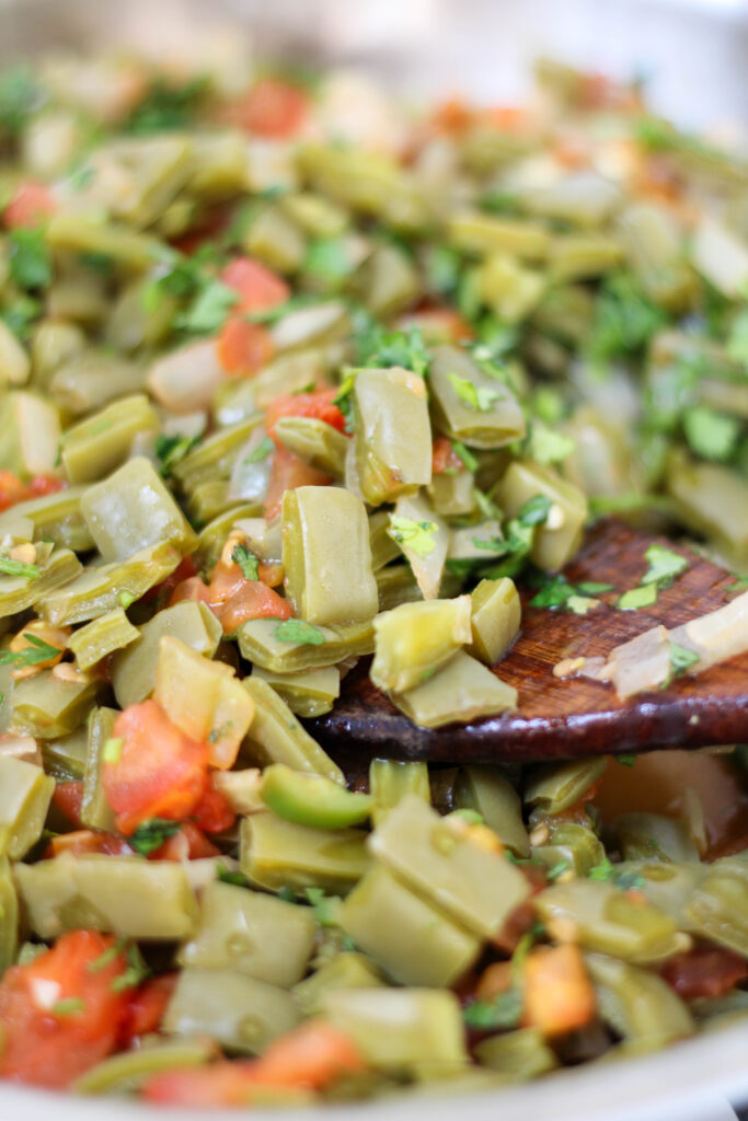 Nopales salad with tomato and onion in a pan with a wood serving spoon