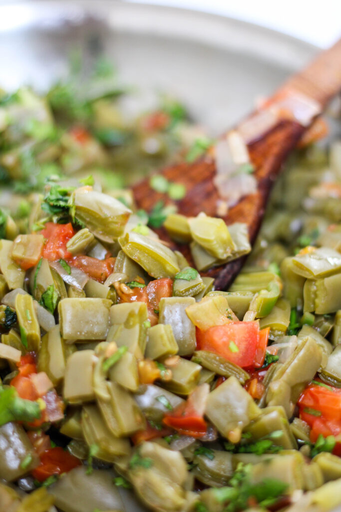 Nopales salad with tomato and onion in a pan with a wood serving spoon