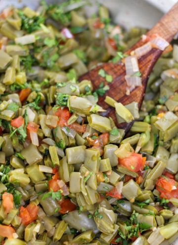 Nopales salad with tomato and onion in a pan with a wood serving spoon
