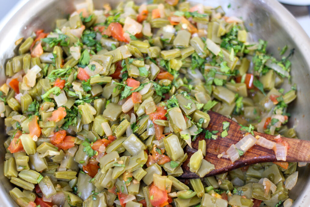Nopalitos salad with tomato and onion in a pan with a wood serving spoon