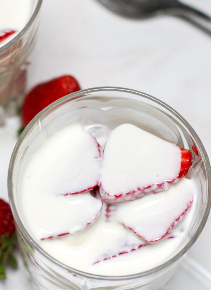Fresas con crema in a short glass on a white table