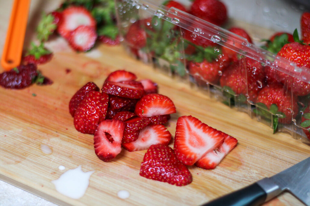 Sliced strawberries on wood cutting board