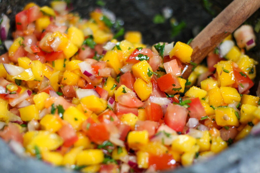 Mango habanero salsa in a grey bowl with tomatoes, red onion and cilantro