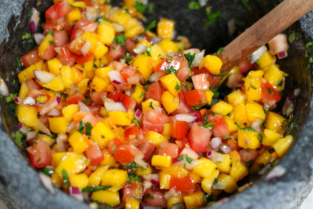 Mango habanero salsa in a grey bowl with tomatoes, red onion and cilantro