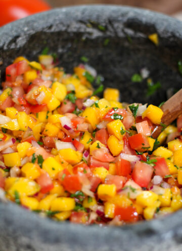 Mango habanero salsa in a grey bowl with tomatoes, red onion and cilantro
