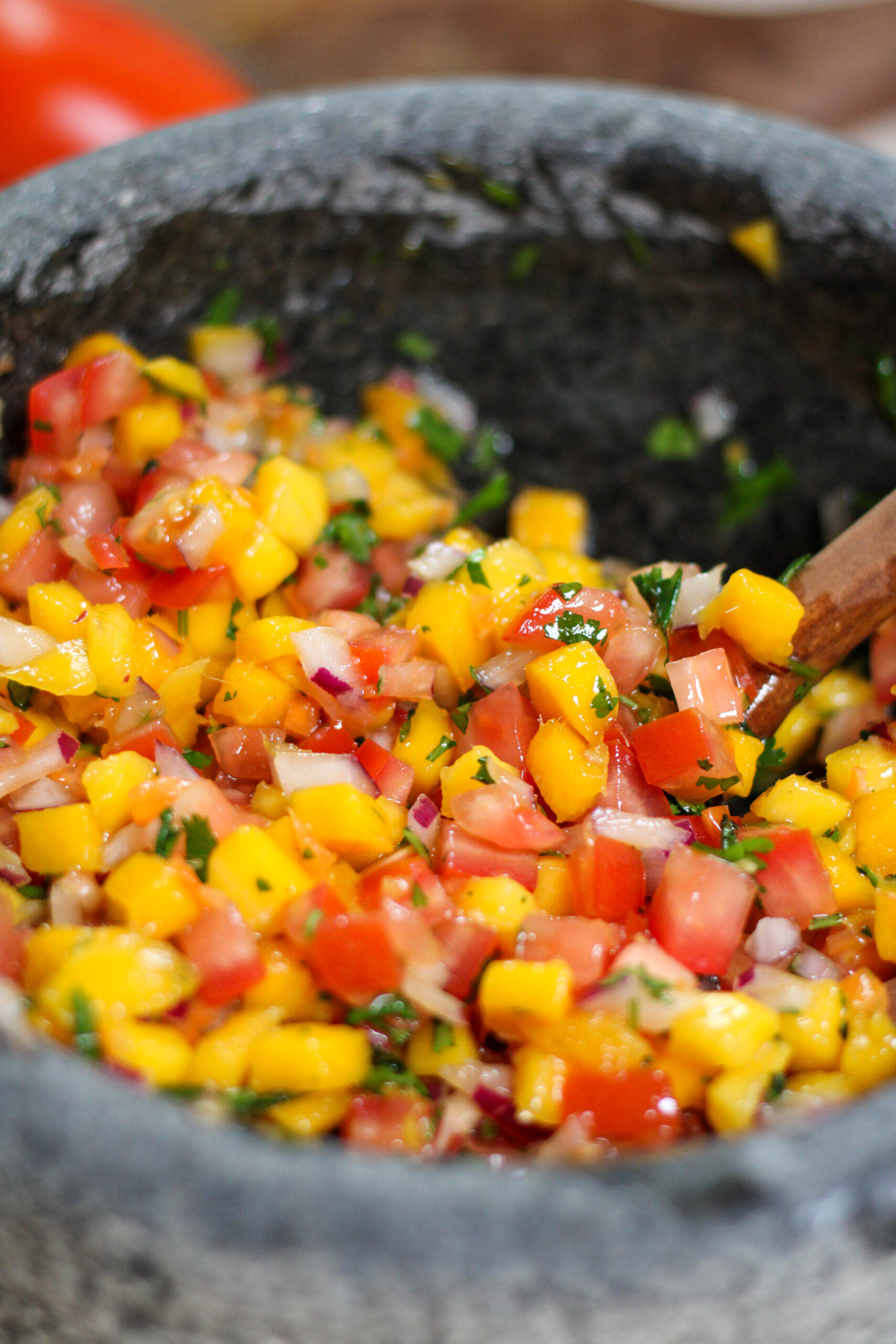 Mango habanero salsa in a grey bowl with tomatoes, red onion and cilantro