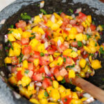 Mango habanero salsa in a bowl with wooden spoon